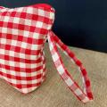 Vista laterale della pochette in cotone a quadretti rossi con manico in tessuto e logo cucito