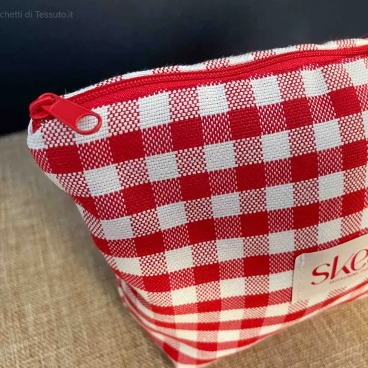 Dettaglio laterale pochette in tessuto quadrettato rosso e bianco con manico in stoffa