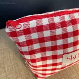 Side detail of a red and white checkered fabric pouch with a fabric handle