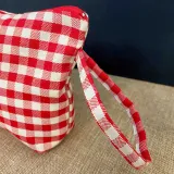 Vue latérale de la pochette en coton à carreaux rouges avec une poignée en tissu et logo cousu