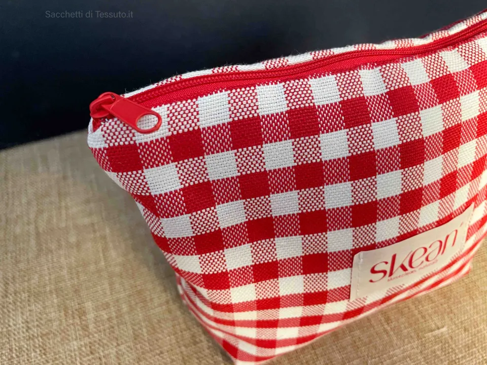 Side detail of a red and white checkered fabric pouch with a fabric handle