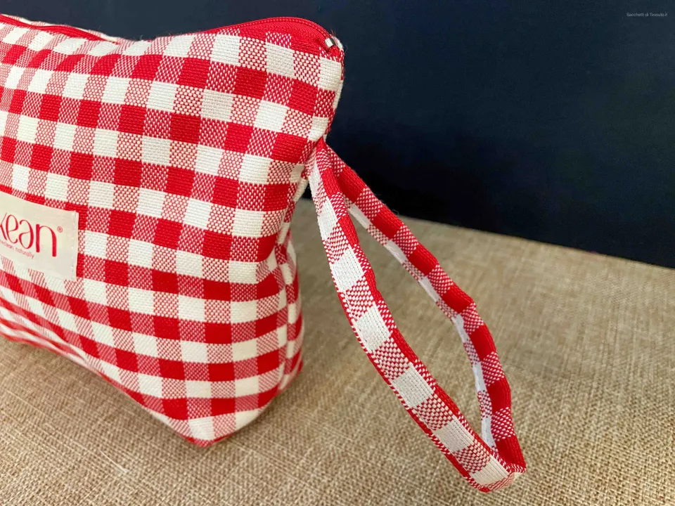 Vue latérale de la pochette en coton à carreaux rouges avec une poignée en tissu et logo cousu